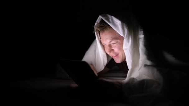 Mladý pohledný muž skandinávské pomocí digitálních tabletu v temné místnosti — Stock video