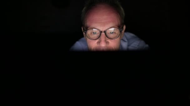 Зрелый скандинавский человек, использующий цифровые планшеты в темной комнате — стоковое видео