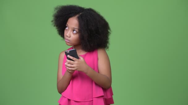 Menina africana bonito nova com cabelo afro usando telefone e pensando — Vídeo de Stock