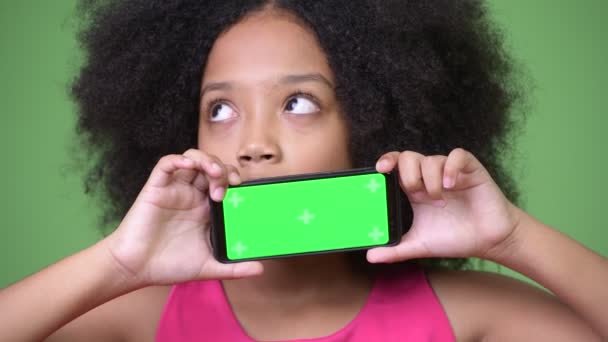 Giovane ragazza africana carina con i capelli afro mostrando telefono mentre si pensa — Video Stock