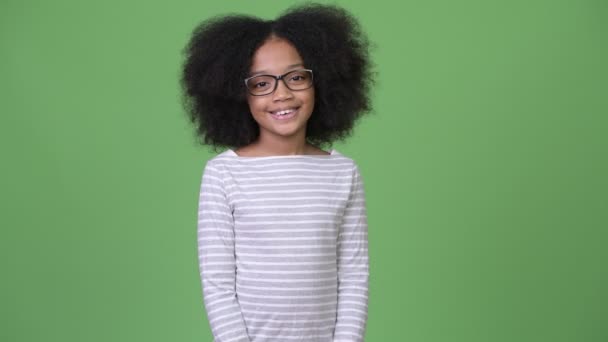 Jong gelukkig Afrikaanse meisje met Afro haar glimlachend tegen groene achtergrond — Stockvideo