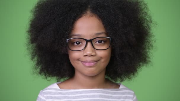 Joven chica africana feliz con el pelo afro sonriendo sobre fondo verde — Vídeo de stock