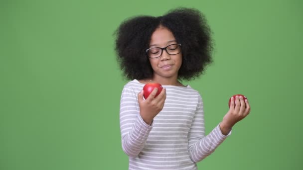 Молодая счастливая африканская девушка с африканскими волосами держит яблоки — стоковое видео