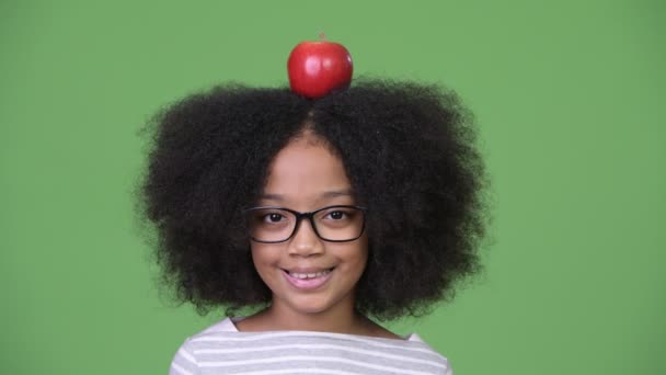 Jovem menina africana feliz com cabelo afro com maçã em cima da cabeça — Vídeo de Stock