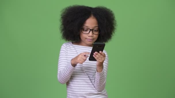 Menina africana bonito nova com cabelo afro usando telefone e tendo dor de cabeça — Vídeo de Stock