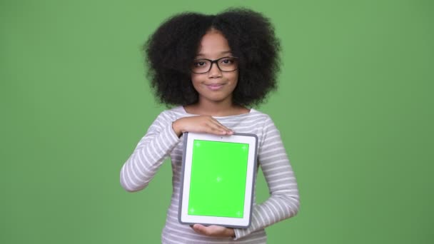 Young cute African girl with Afro hair showing digital tablet to camera — Stock Video