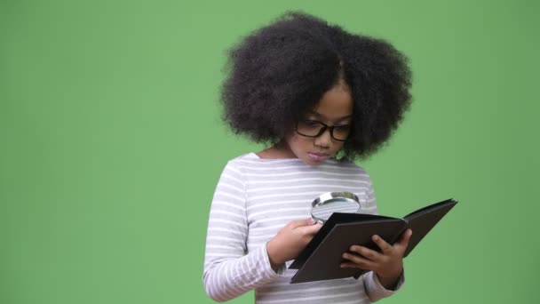 Joven linda chica africana con pelo afro estudiando sobre fondo verde — Vídeos de Stock