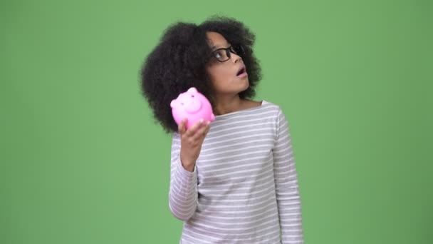 Jovem menina africana bonito com cabelo afro segurando porquinho banco — Vídeo de Stock