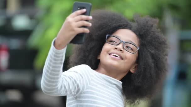 Ung Söt afrikansk flicka med Afro hår videosamtal med telefonen i gatorna utomhus — Stockvideo