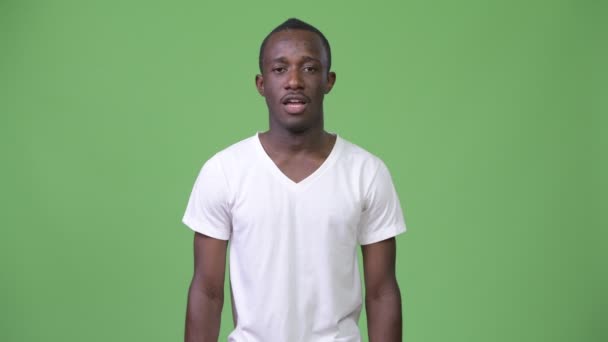 Joven hombre africano cansado hablando sobre fondo verde — Vídeos de Stock