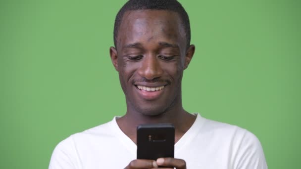 Giovane uomo africano utilizzando il telefono sullo sfondo verde — Video Stock