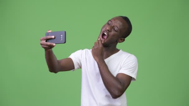 Jovem africano tomando selfie contra fundo verde — Vídeo de Stock