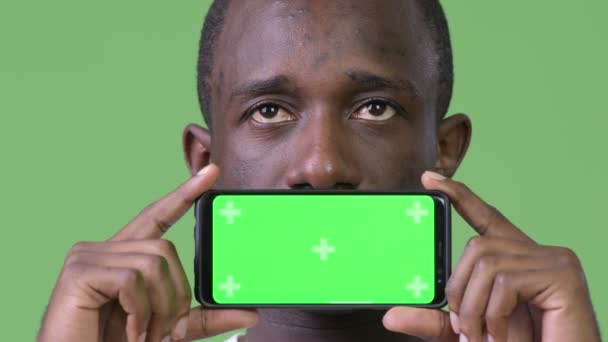 Jovem homem africano pensando ao mostrar telefone — Vídeo de Stock