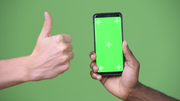 Deux mains multiethniques montrant le téléphone tout en donnant pouces vers le haut — Video
