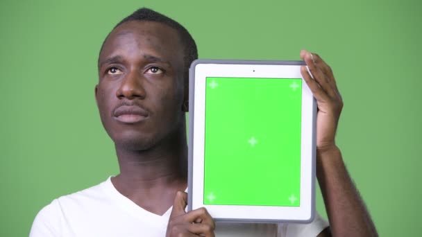 Молодой африканский человек думает, показывая цифровой планшет — стоковое видео