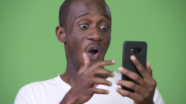 Jeune homme africain heureux regardant choqué tout en utilisant le téléphone — Video