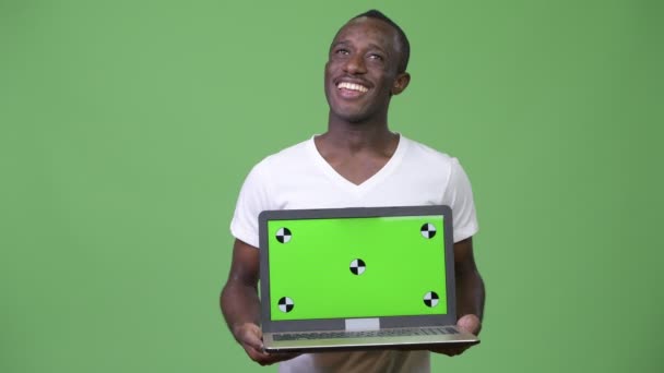 Giovane uomo africano pensando mentre mostra il computer portatile — Video Stock