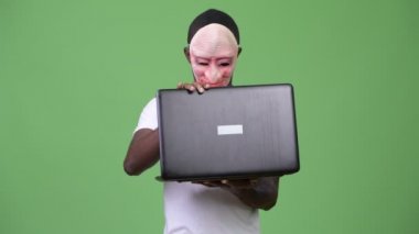 Maske ve gösteren orta parmak dizüstü bilgisayar kullanırken giyen genç Afrika adam