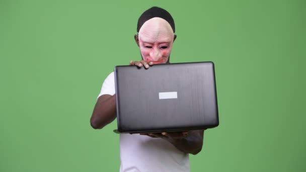노트북을 사용 하는 동안 마스크와 보여주는 가운데 손가락을 입고 젊은 아프리카 남자 — 비디오
