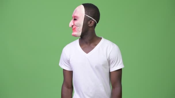 Молодой африканский мужчина смеется в маске и показывает средний палец — стоковое видео
