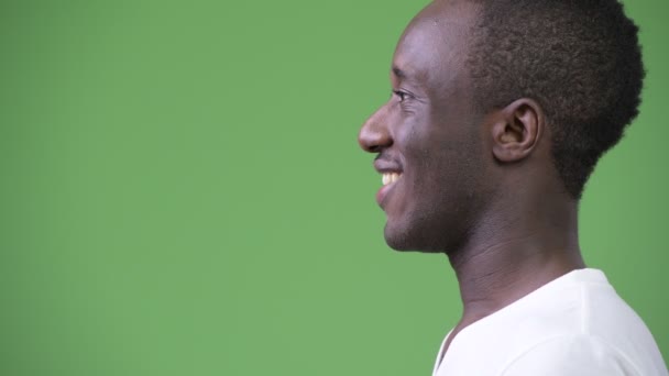 Vista del perfil del joven hombre africano feliz sobre fondo verde — Vídeo de stock