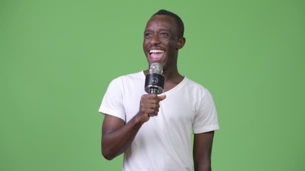 Joven hombre africano feliz sonriendo mientras habla en el micrófono — Vídeo de stock