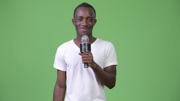 Boldog afrikai fiatalember mosolyogva, miközben beszél a mikrofon — Stock videók