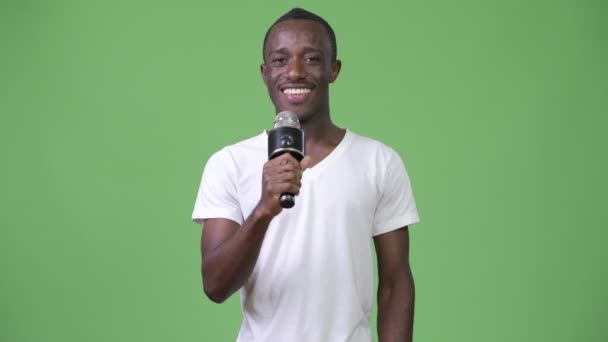 Ευτυχισμένος αφρικανική νεαρός χαμογελώντας ενώ μιλώντας μικρόφωνο — Αρχείο Βίντεο