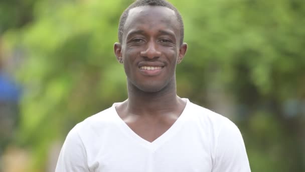 Молодой счастливый африканский мужчина улыбается на улице — стоковое видео