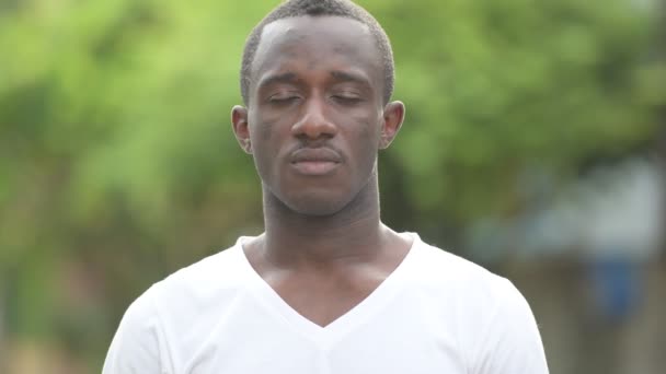 Gelukkig Afrikaanse jongeman ontspannen met ogen gesloten in de straten buiten — Stockvideo