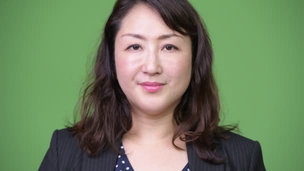 Mature beautiful Asian businesswoman against green background — Stock Video