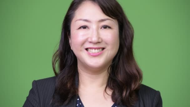 हिरव्या पार्श्वभूमी विरुद्ध मेच्यूर सुंदर एशियन व्यवसाय महिला — स्टॉक व्हिडिओ