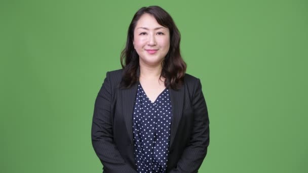 Rijpe mooie Aziatische zakenvrouw tegen groene achtergrond — Stockvideo