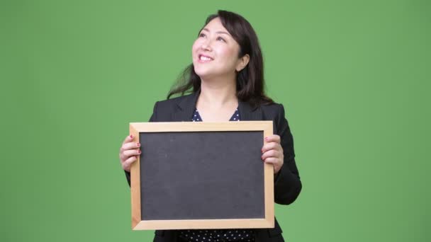 黒板を見せながら考えて成熟した美しいアジア女性実業家 — ストック動画