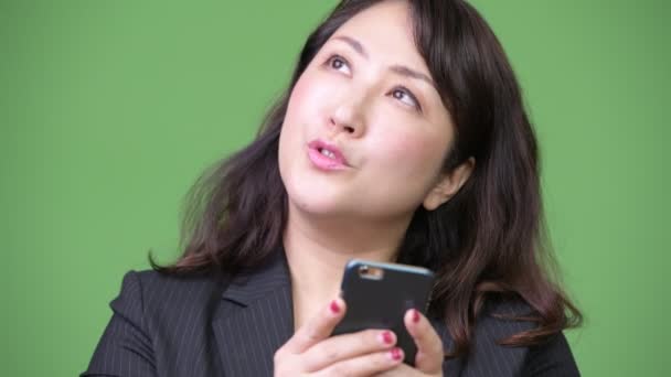 Зрілі красиві азіатські бізнес-леді думаючи, що під час використання телефону — стокове відео