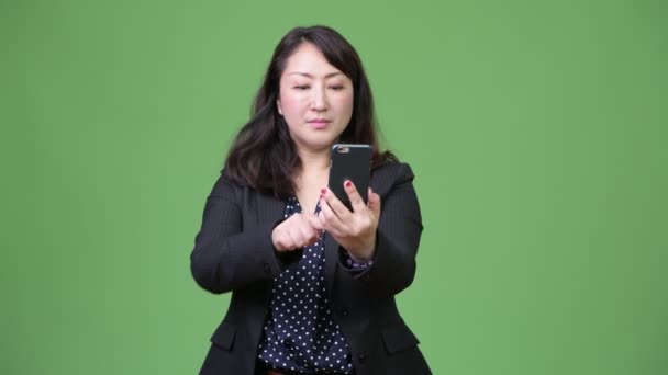 Зрілі красиві азіатські бізнес-леді за допомогою телефону і даючи великі пальці вниз — стокове відео