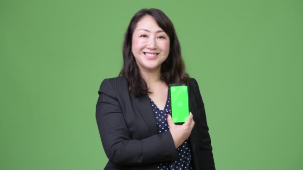Зрелая красивая азиатская бизнесвумен показывает телефон — стоковое видео