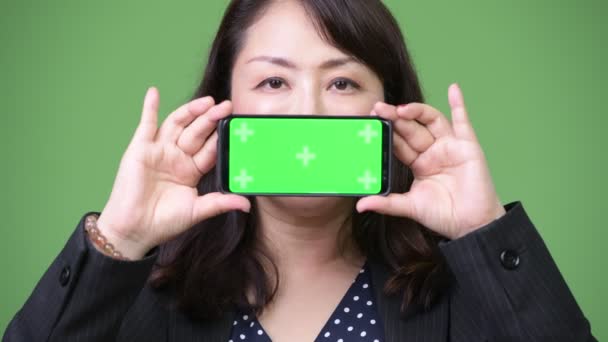 Mature beautiful Asian businesswoman showing phone — Stock Video