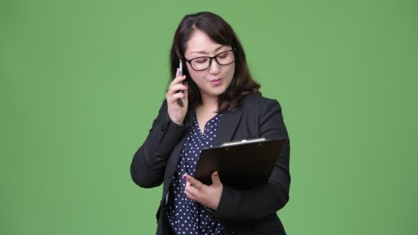 Rijpe mooie Aziatische zakenvrouw met behulp van de telefoon houd van Klembord — Stockvideo