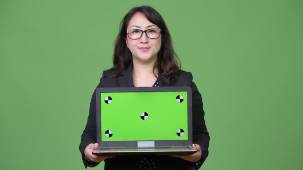 Зрілі красиві азіатські бізнес-леді показ ноутбук на зеленому тлі — стокове відео