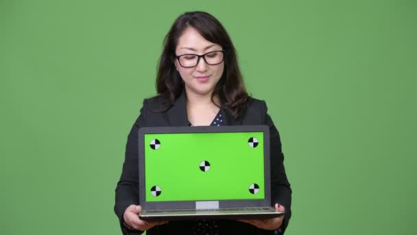 성숙한 아름 다운 아시아 사업가 녹색 배경에 노트북을 보여주는 — 비디오