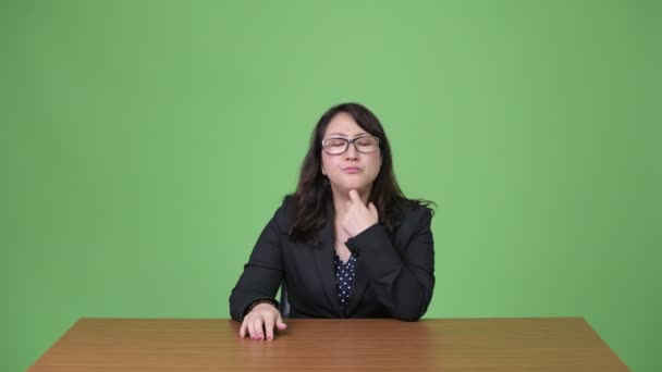 Зрілі нудно азіатських бізнес-леді думаючи, сидячи за столом — стокове відео