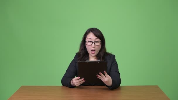 Érett gyönyörű ázsiai üzletasszony olvasó csipeszes írótábla — Stock videók