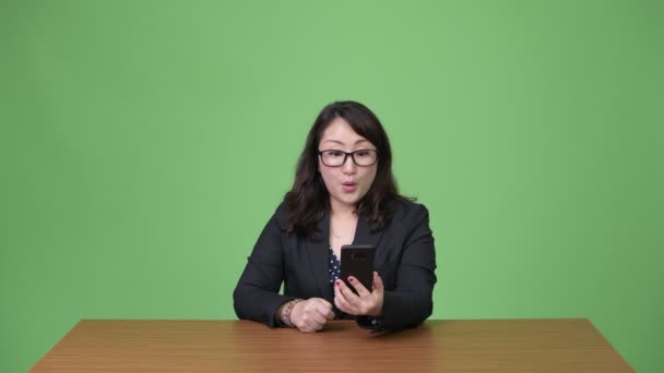 Reif schön asiatisch unternehmerin using phone und getting gut news — Stockvideo