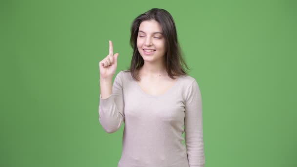 Joven feliz hermosa mujer pensando mientras señala con el dedo hacia arriba — Vídeos de Stock