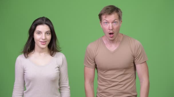 Jovem casal olhando chocado juntos contra fundo verde — Vídeo de Stock