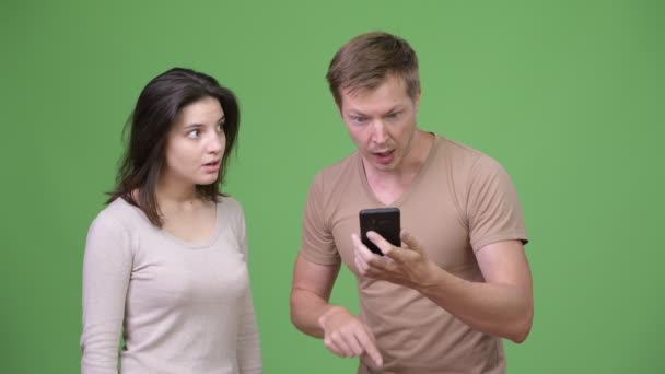 Hombre joven usando el teléfono con la mujer joven mirando sorprendido — Vídeos de Stock