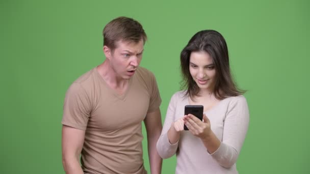 Young woman using phone with young man looking shocked — Stock Video