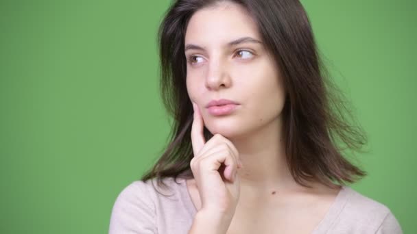 Junge schöne Frau denkt vor grünem Hintergrund — Stockvideo
