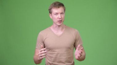 Genç yakışıklı İskandinav adam yeşil arka plana karşı bir şey sunmak